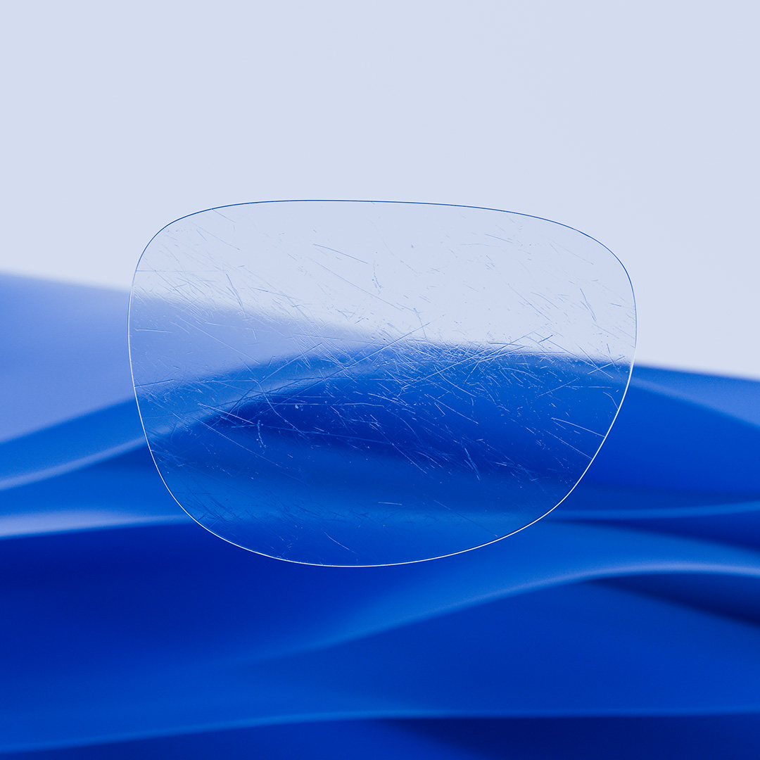 Rozdělená brýlová čočka s jednou stranou čistou a čirou, která je opatřena povrchovou úpravou ZEISS DuraVision, a druhou stranou se škrábanci.