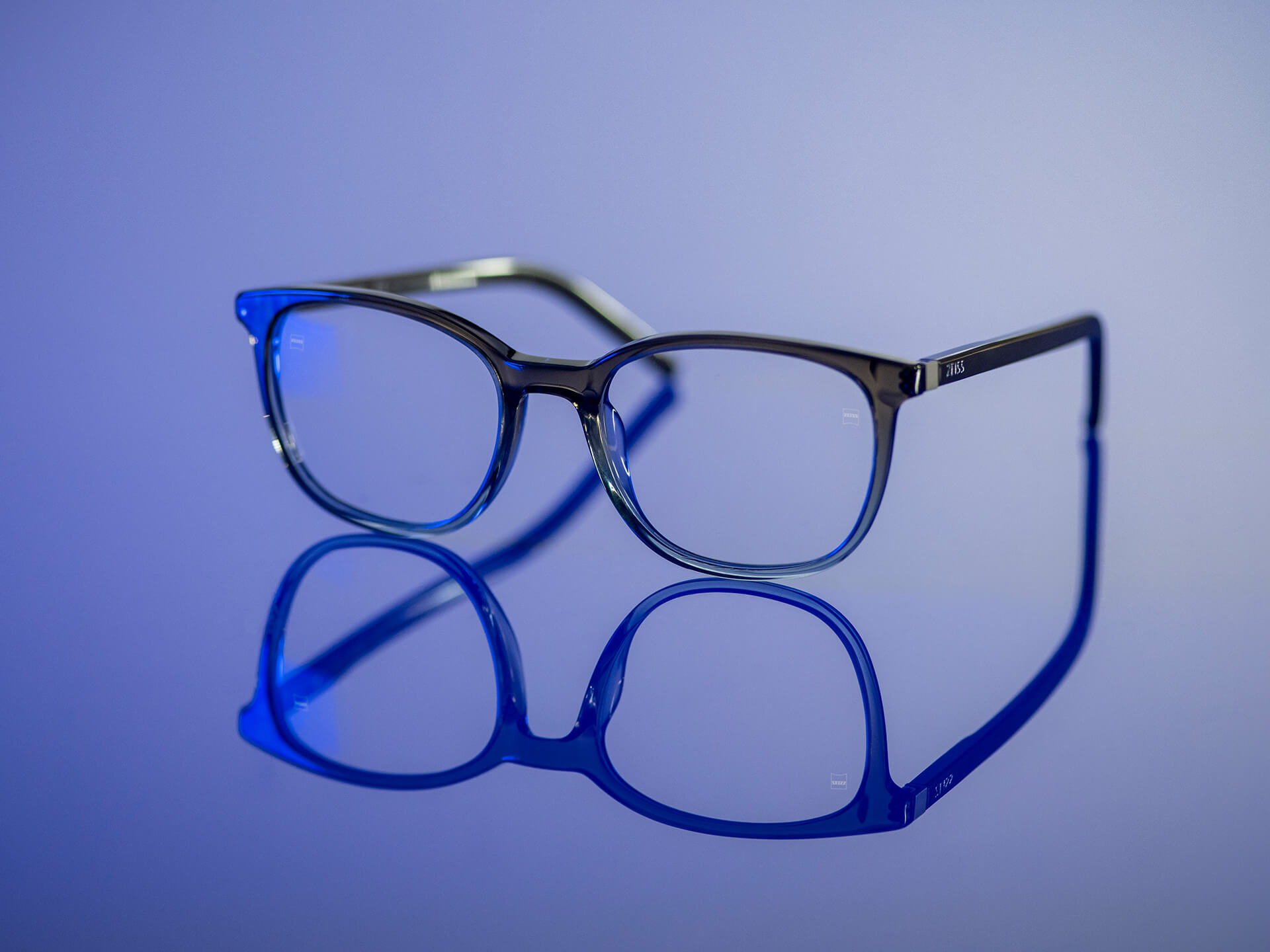 Brýle v namodralém světle osazené čočkami ZEISS z materiálu BlueGuard. Na čočkách je vidět jen velmi omezený modrý odraz.