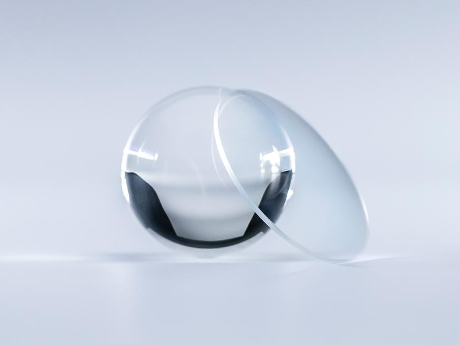 Brýlové čočky s povrchovou úpravou ZEISS Platinum jsou v porovnání se skleněným míčem vedle nich křišťálově čisté a bez odrazů.