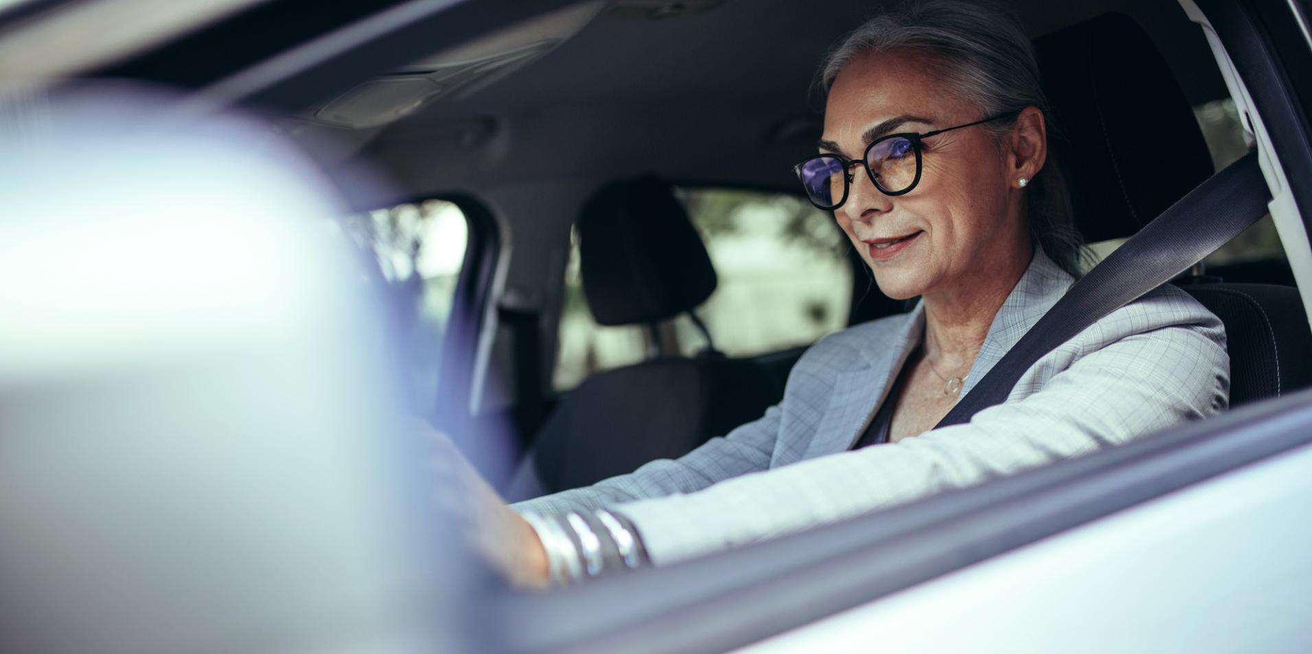 Dospělá žena s brýlemi s čočkami ZEISS DriveSafe v autě.
