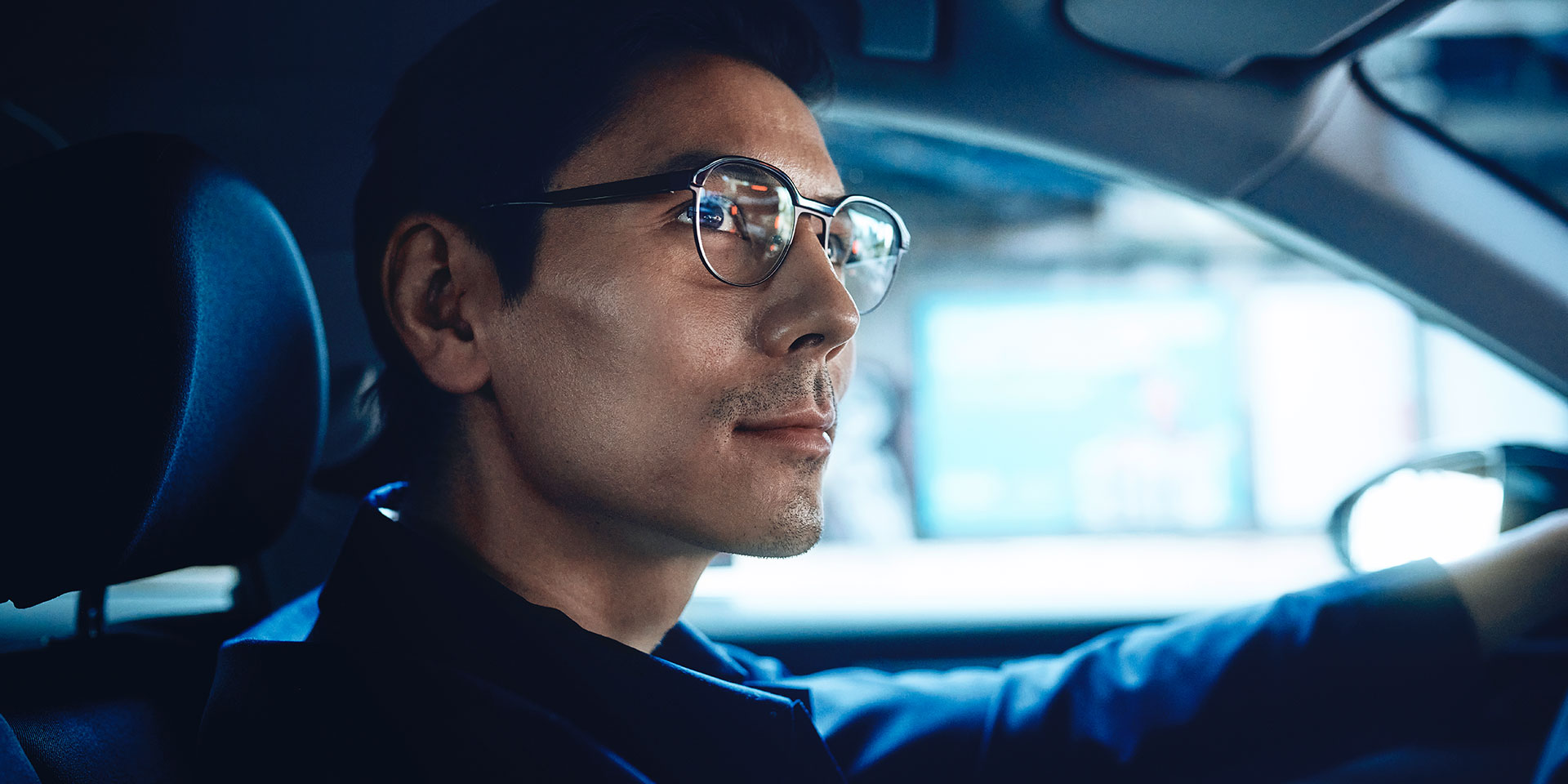 Muž řídí auto, vypadá sebevědomě a na tváři má mírný úsměv. Na sobě má jednoohniskové čočky ZEISS DriveSafe.