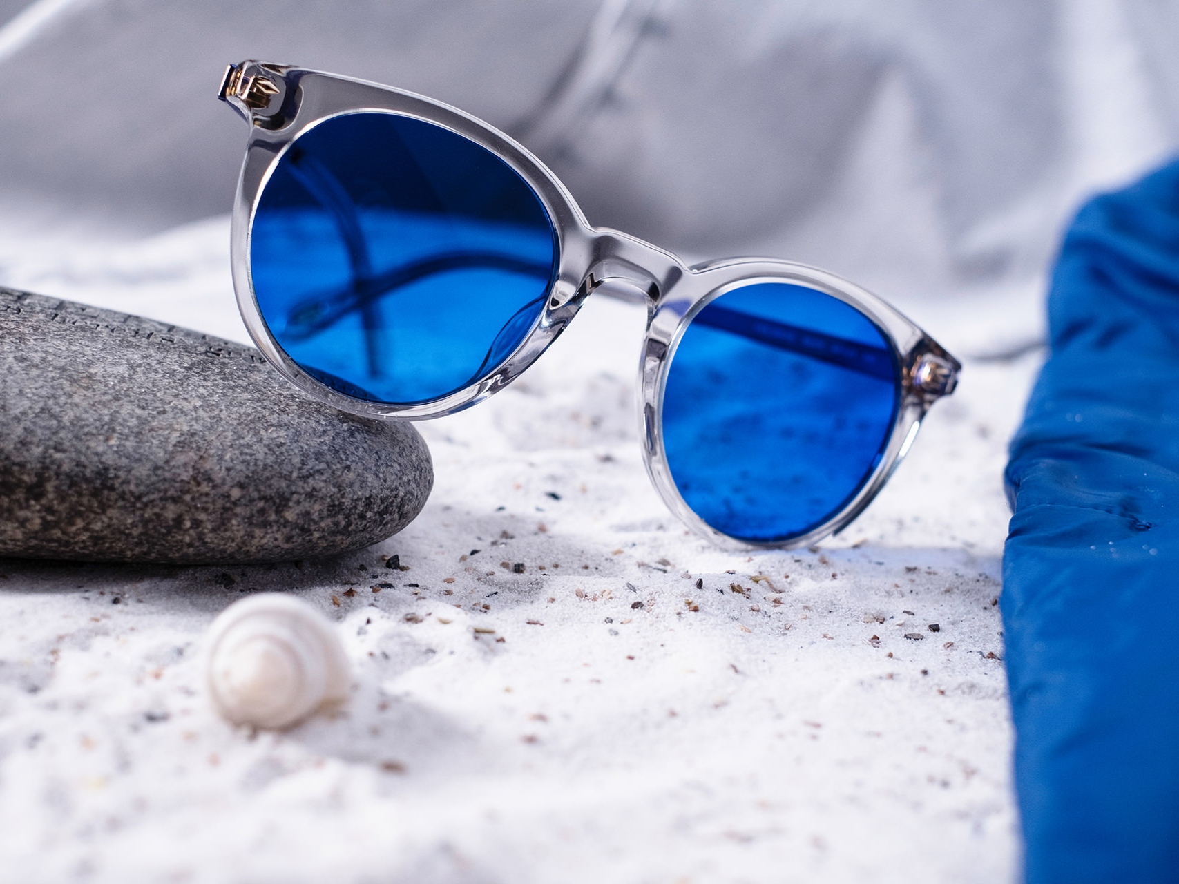 Obrázek páru slunečních brýlí s modrými skly, které jsou opřené o kámen