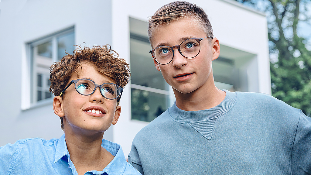 Mladý chlapec se dívá na staršího chlapce. Oba na sobě mají nasazené brýle s jednoohniskovými čočkami ZEISS SmartLife Young